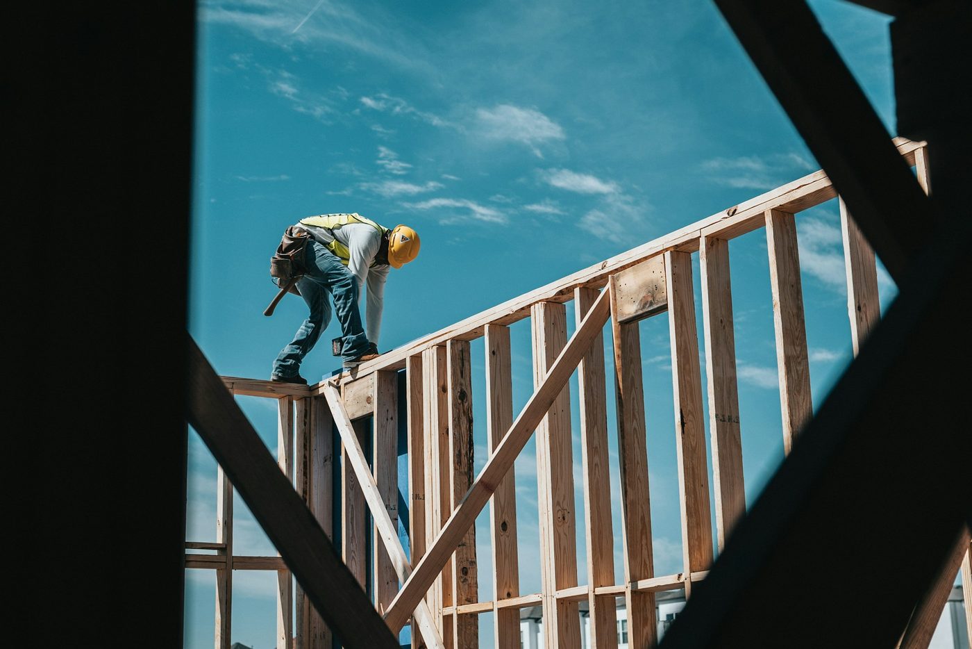 A construction worker in a hard hat framing a building