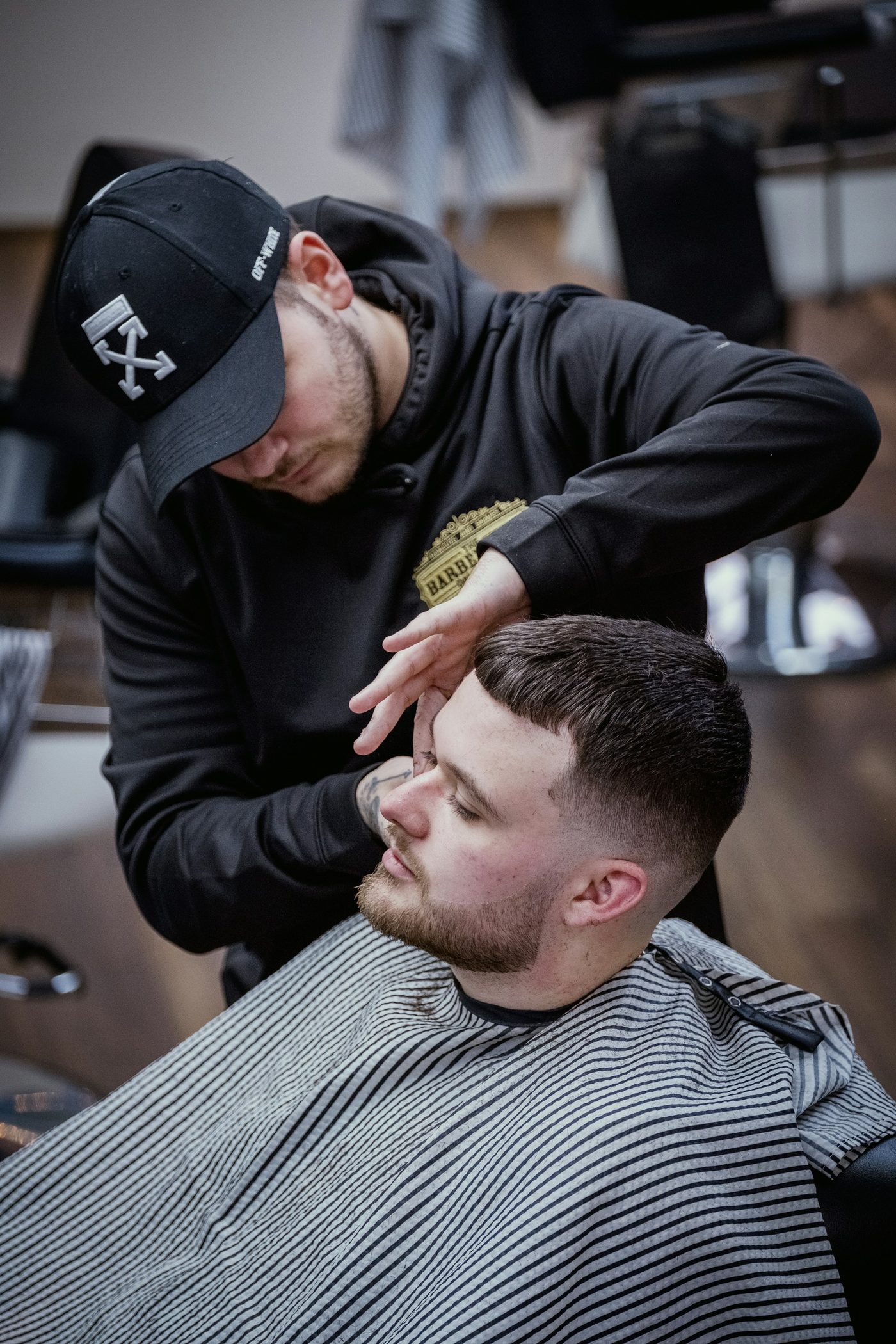 A barber cutting a client's hair in a barbershop