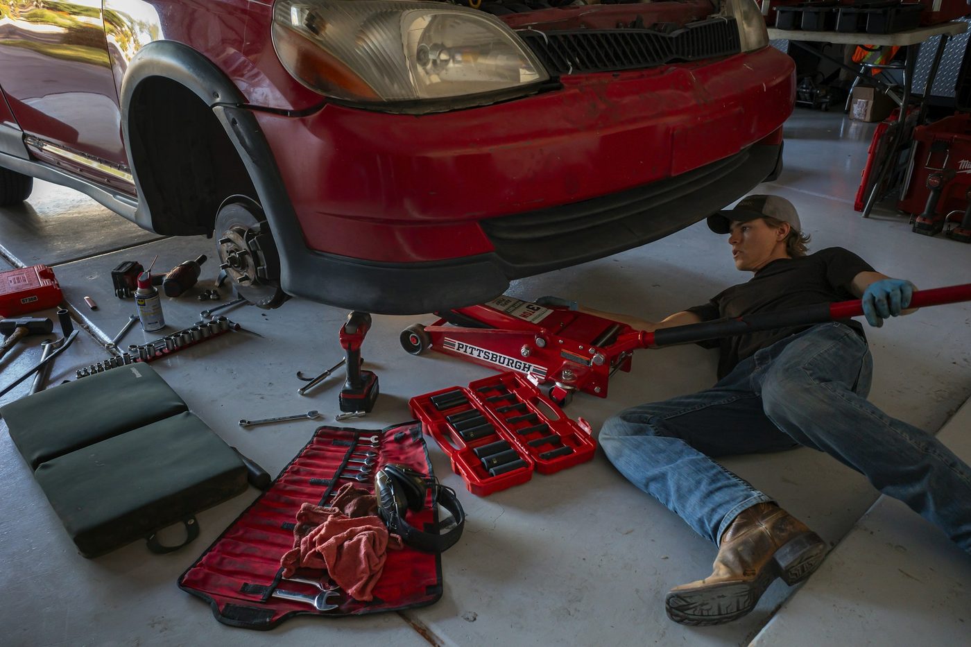 A mechanic working underneath a car in an auto repair shop